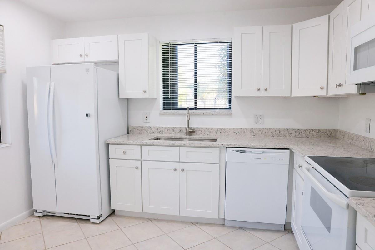 A kitchen features white cabinetry, a white refrigerator, a dishwasher, and speckled granite countertops — 428 Lakeview Drive # 201, Weston FL 33326, WESTON, FL