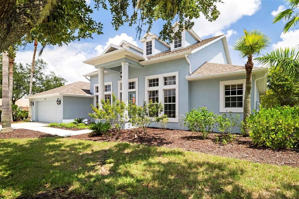 A light blue two-story house with a white-pillared entryway and a two-car garage — 1111 BRAMBLING COURT, BRADENTON, FL