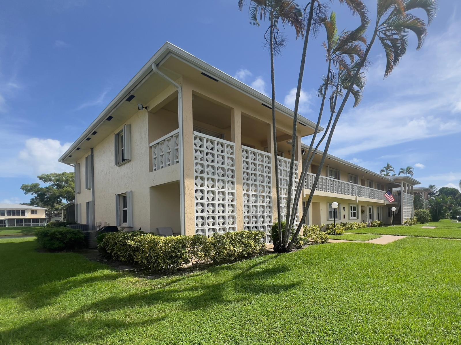 An aerial view of a multi-story apartment building with a lake and surrounding landscaping — 1421 NW 19th Terrace # 102, Delray Beach FL 33445, DELRAY BEACH, FL