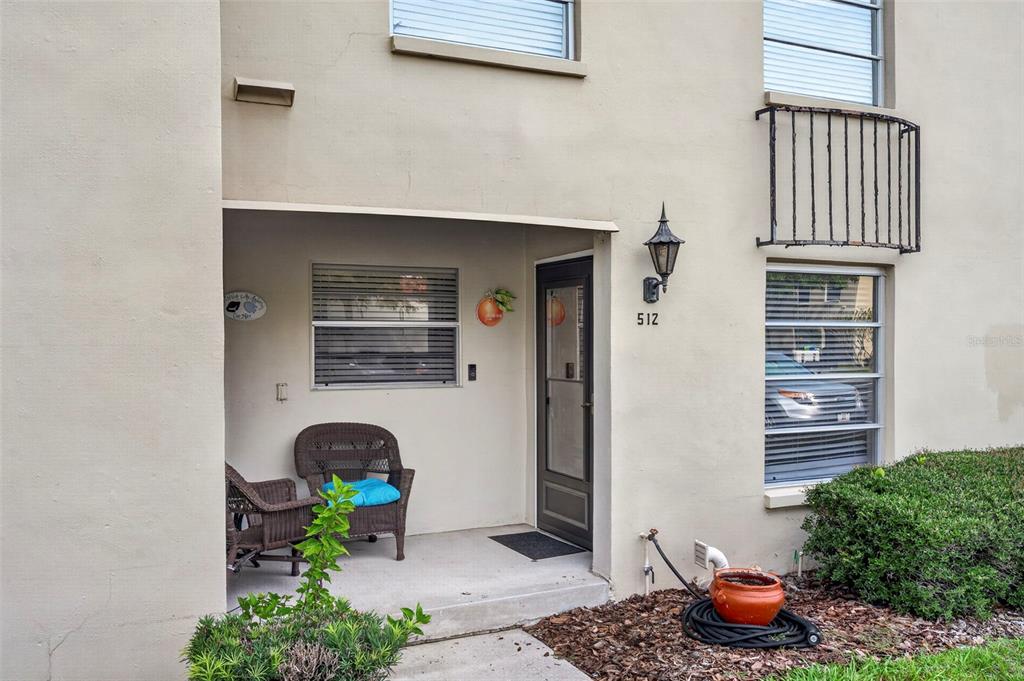 A tan exterior view of a residential unit entrance with a small covered patio area — 2700 BAYSHORE BOULEVARD UNIT 512, DUNEDIN, FL