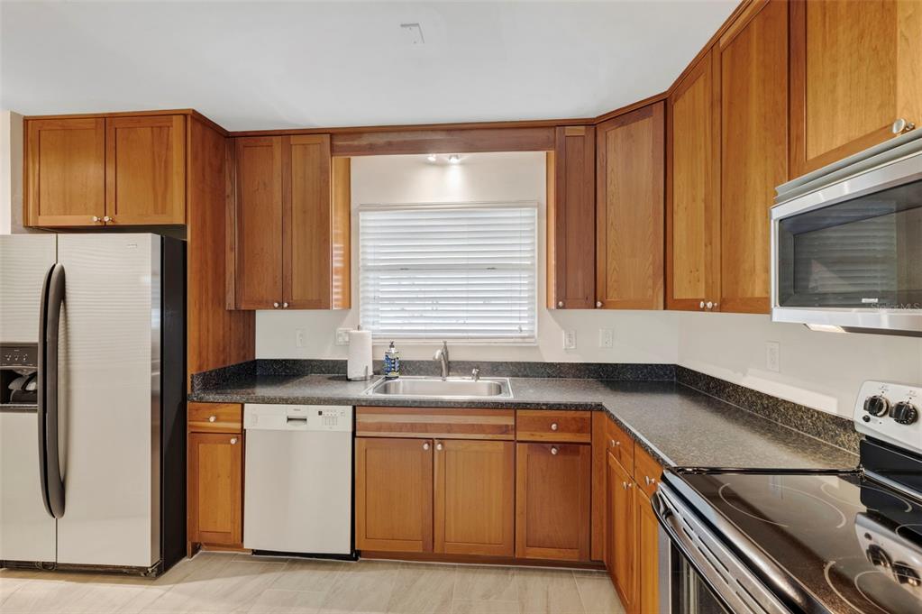 A kitchen features wood cabinets, stainless steel appliances, and dark countertops with a sink — 2700 BAYSHORE BOULEVARD UNIT 512, DUNEDIN, FL