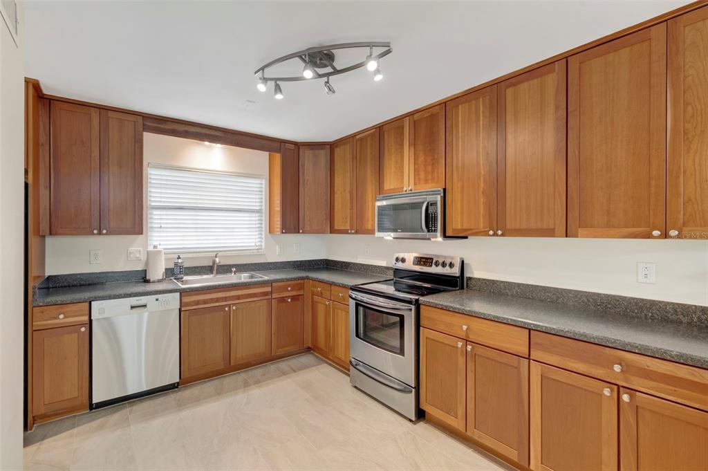 A kitchen features wood cabinets, stainless steel appliances, and dark countertops — 2700 BAYSHORE BOULEVARD UNIT 512, DUNEDIN, FL