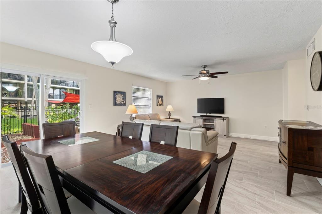 A dining area with a dark wood table opens into a living room with tile floors — 2700 BAYSHORE BOULEVARD UNIT 512, DUNEDIN, FL