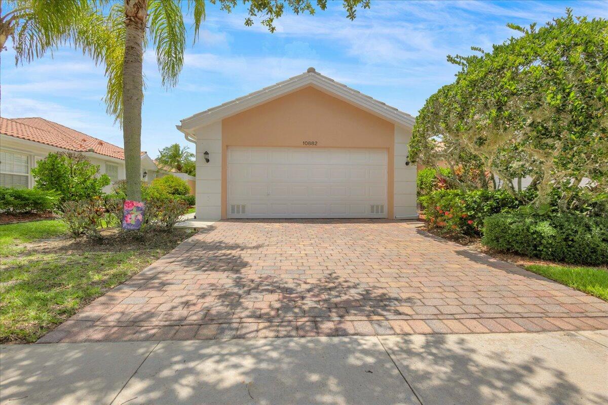 A beige house with a white garage door and a paved driveway under a blue sky — 10882 SW Dardanelle Drive, FL 34987, FL