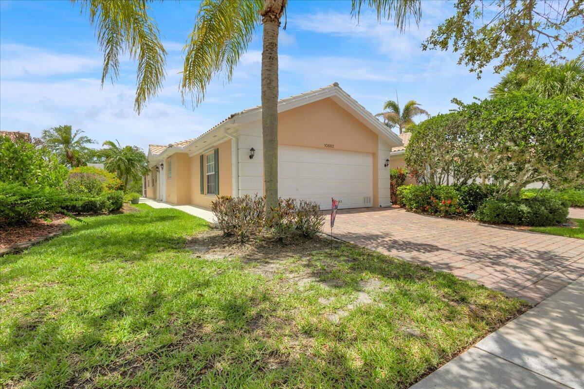 A single-story house with a beige stucco exterior, a two-car garage, and a brick driveway — 10882 SW Dardanelle Drive, FL 34987, FL