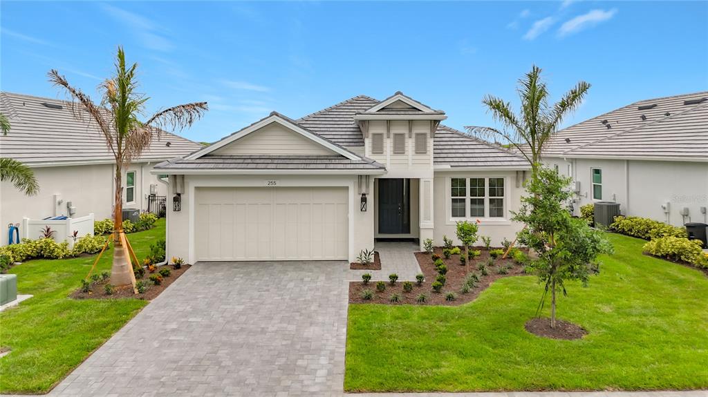 A single-story house with a beige exterior, a two-car garage, and a paved driveway — 255 MONET TRAIL, BRADENTON, FL
