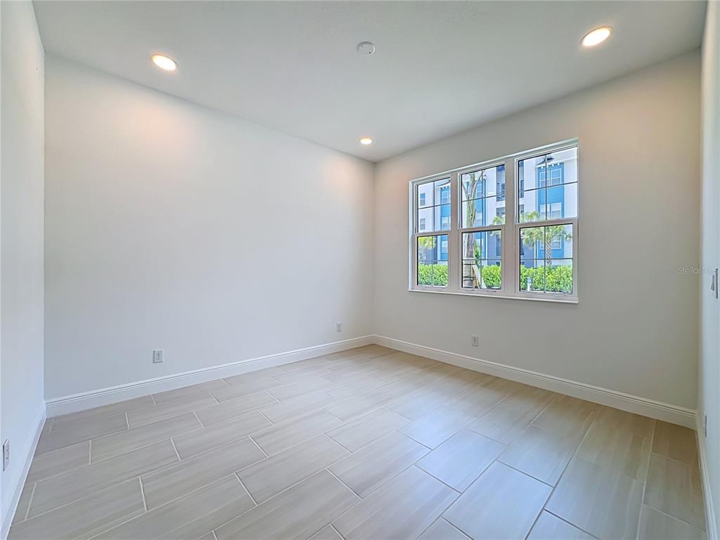 An empty room features light-colored tile flooring, white walls, recessed lighting, and a large window — 255 MONET TRAIL, BRADENTON, FL