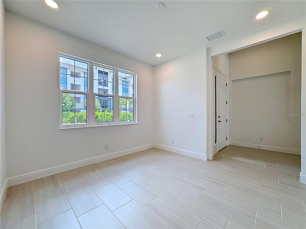 A bright, empty room features light-colored tile flooring, white walls, and a large window — 255 MONET TRAIL, BRADENTON, FL
