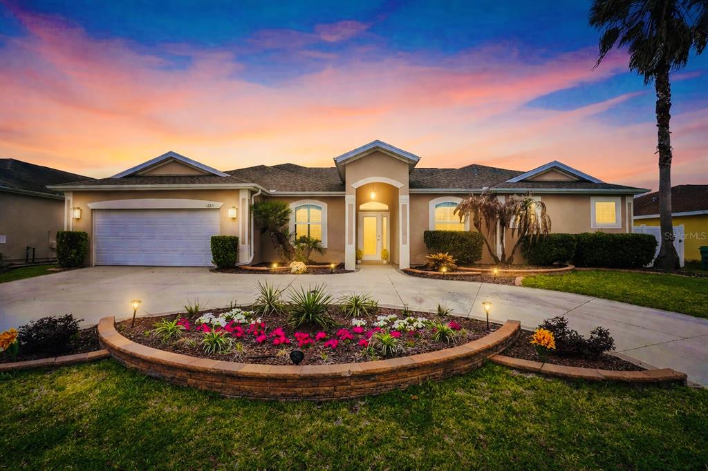 A single-story house with a beige exterior, a two-car garage, and a curved garden bed — 12371 NE 48TH CIRCLE, OXFORD, FL