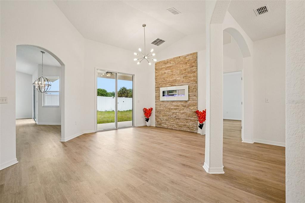 A living room with light wood floors, a stone fireplace, and a sliding glass door — 12371 NE 48TH CIRCLE, OXFORD, FL
