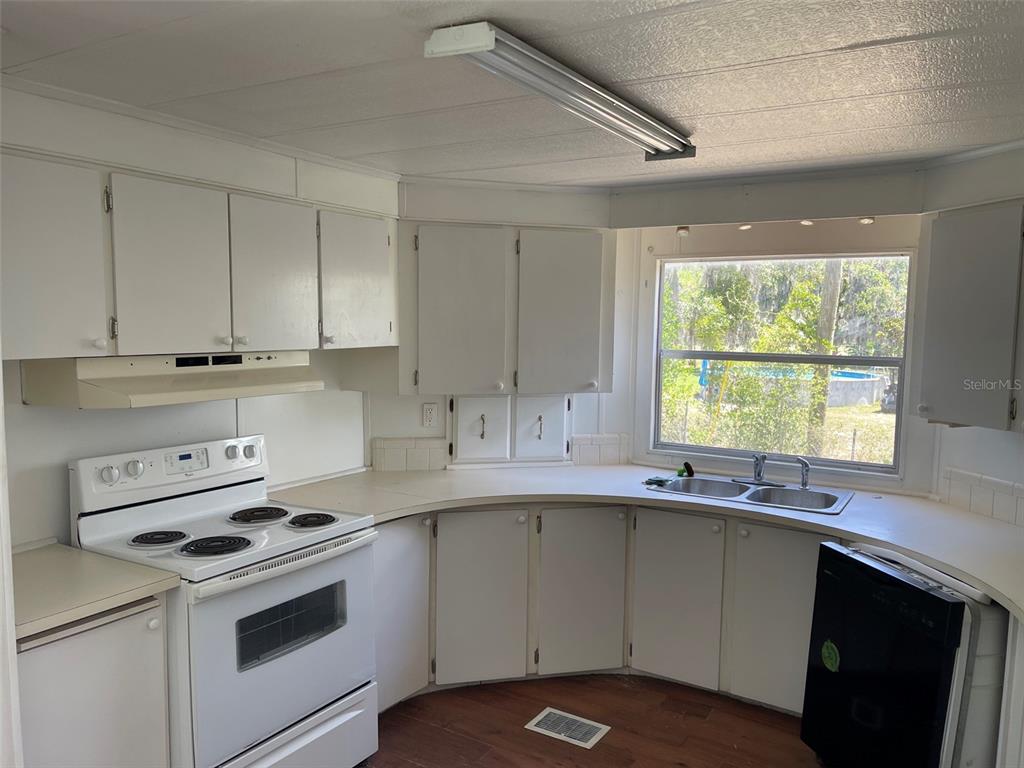 A kitchen with white cabinets, white appliances, a double sink, and wood-look flooring — 16329 CALDWELL LANE, SPRING HILL, FL