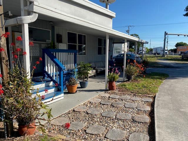 A building exterior features a blue wooden staircase leading to a covered porch area — 8680 Us Highway 441 SE, Okeechobee FL 34974, OKEECHOBEE, FL