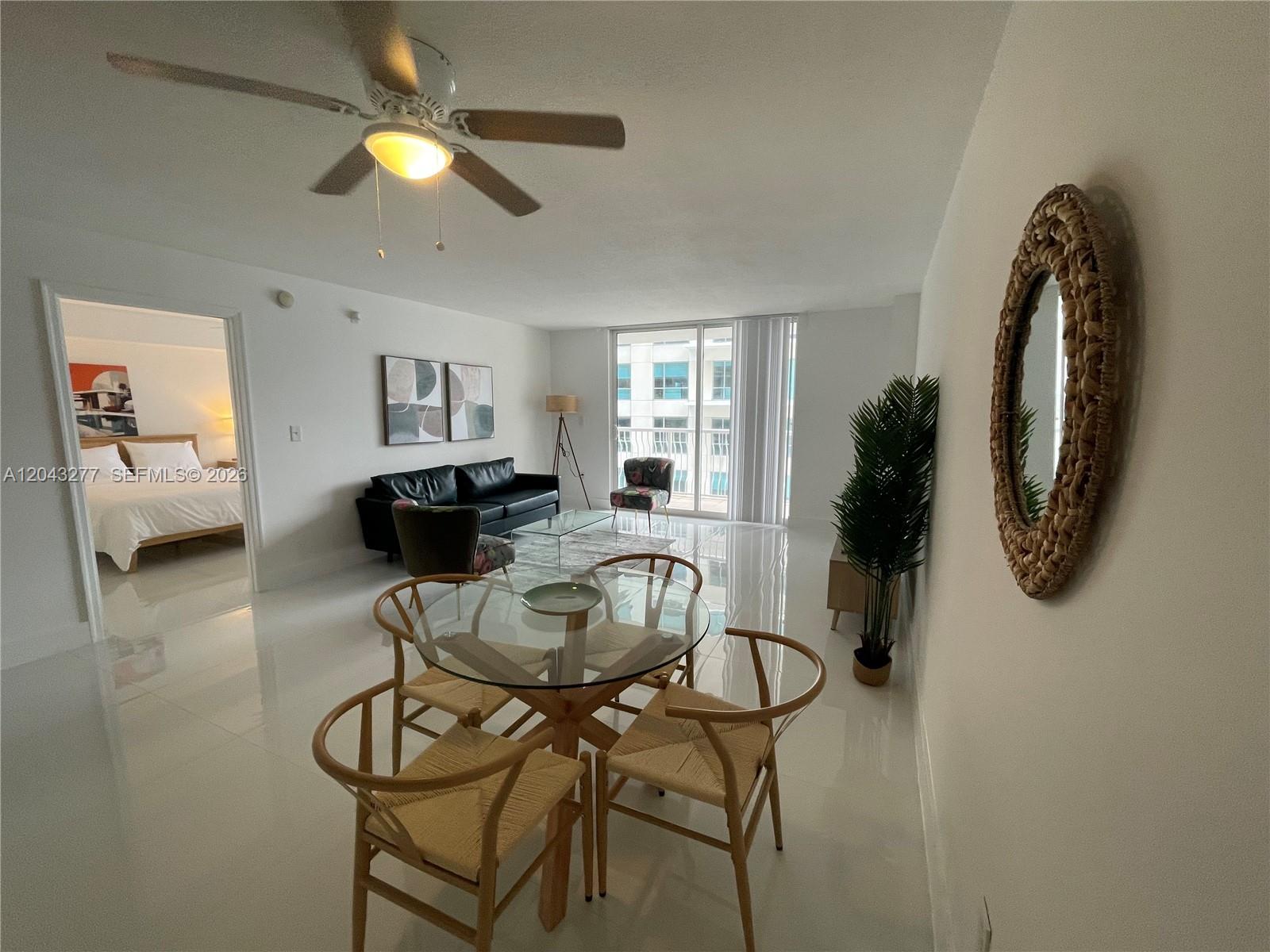 A living and dining area features white tile floors, a glass dining table, and a balcony — 1200 BRICKELL BAY DR # 3104, Miami FL 33131, MIAMI, FL