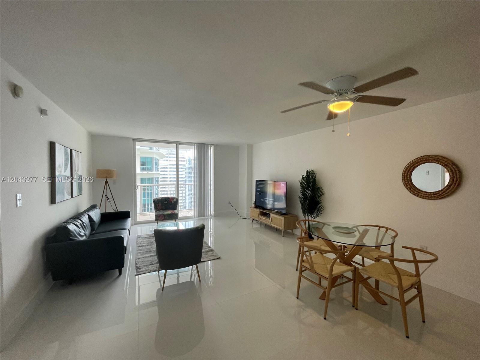 A living and dining area features white tile floors, a black sofa, and a glass table — 1200 BRICKELL BAY DR # 3104, Miami FL 33131, MIAMI, FL