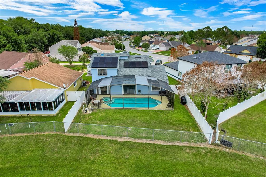 An aerial view shows a two-story house with solar panels, a screened pool, and a fenced yard — 12908 DETROIT WOODS COURT, ORLANDO, FL