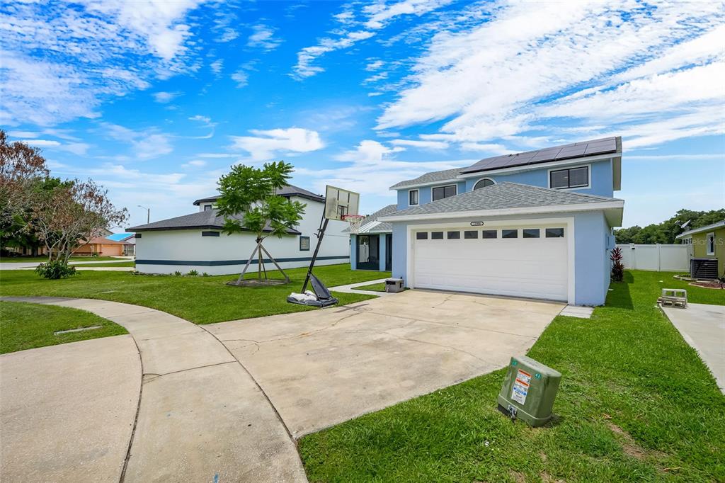 A two-story blue house with a white garage door, solar panels, and a basketball hoop — 12908 DETROIT WOODS COURT, ORLANDO, FL