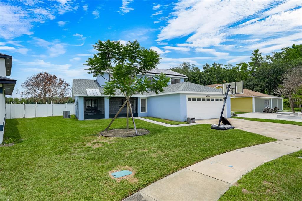 A light blue two-story house with a garage, a basketball hoop, and a front lawn — 12908 DETROIT WOODS COURT, ORLANDO, FL