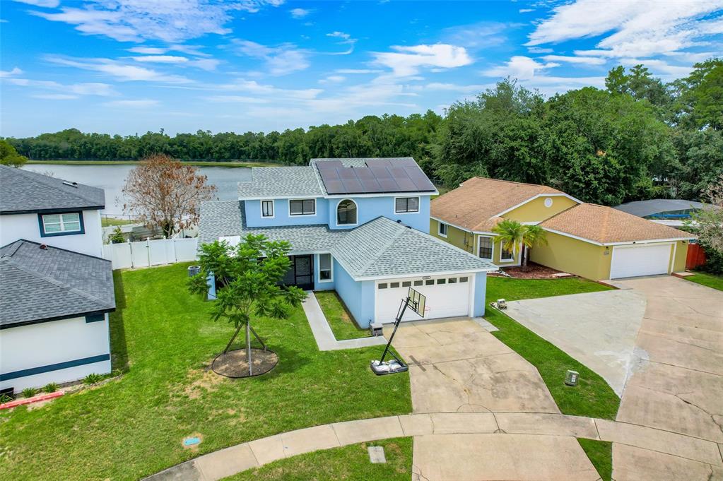 An aerial view of a light blue two-story house with solar panels and a garage — 12908 DETROIT WOODS COURT, ORLANDO, FL