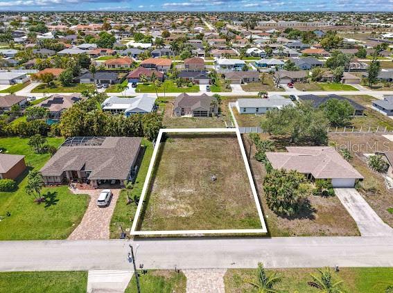 An aerial view shows a vacant rectangular residential lot situated between two existing houses — 4406 SW 5TH PLACE, CAPE CORAL, FL
