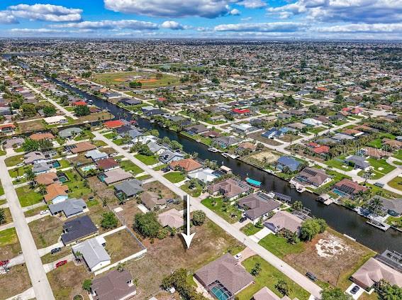 An aerial view shows a vacant residential lot with a white arrow pointing toward it — 4406 SW 5TH PLACE, CAPE CORAL, FL