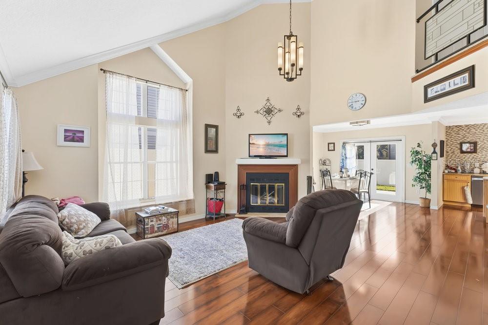 A living room with hardwood floors, a fireplace, vaulted ceilings, and a large window — 2640 WAYMEYER DRIVE, ORLANDO, FL