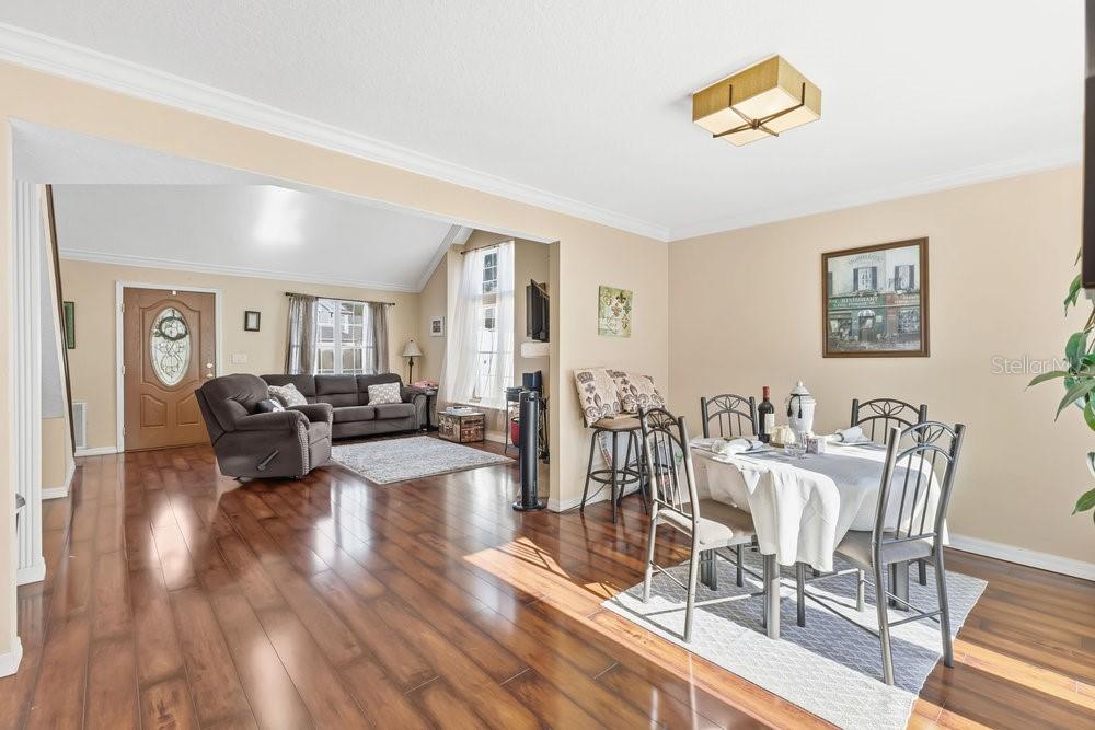 A dining area with a table and chairs opens into a living room with hardwood floors — 2640 WAYMEYER DRIVE, ORLANDO, FL