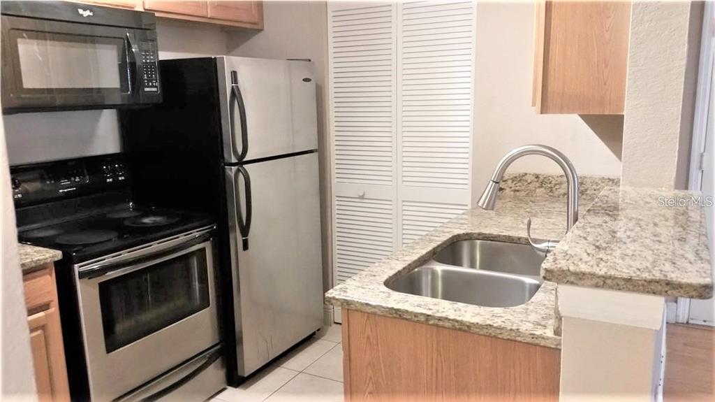 A kitchen features stainless steel appliances, light wood cabinets, and granite countertops — 1049 S HIAWASSEE ROAD UNIT 3416, ORLANDO, FL