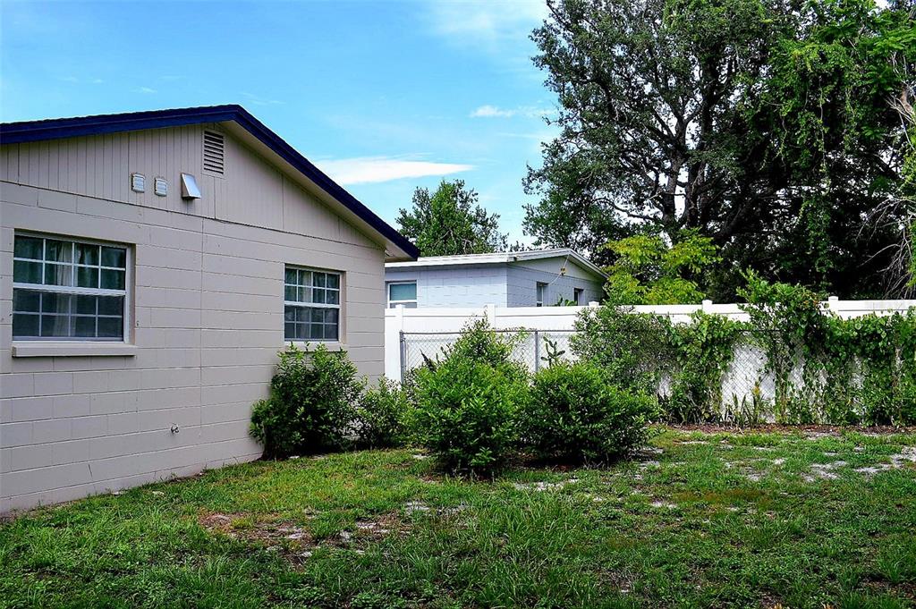 The exterior of a beige concrete block house with a white fence and green lawn — 4306 W LA SALLE STREET, TAMPA, FL