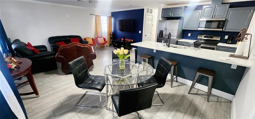 An open-concept living room and kitchen featuring gray cabinets, stainless steel appliances, and tile flooring — 4306 W LA SALLE STREET, TAMPA, FL