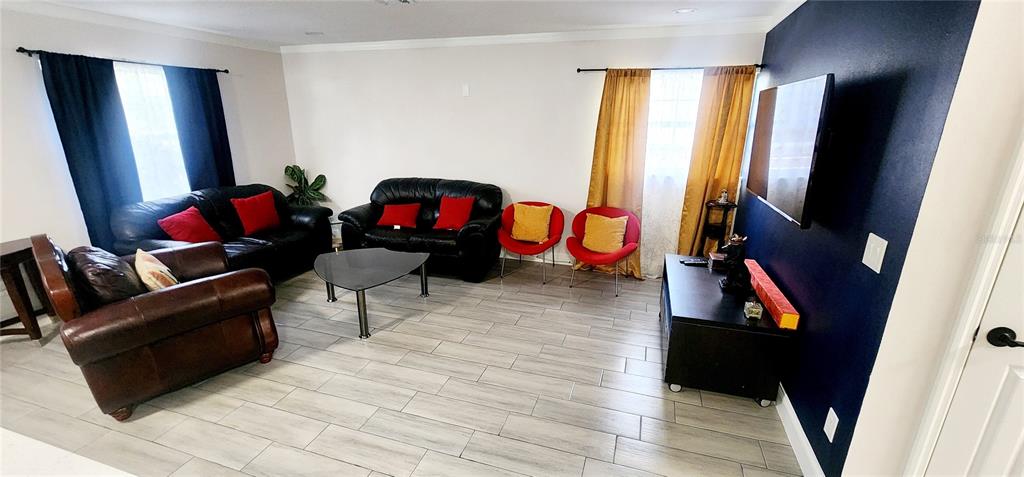 A living room features a black leather sofa, brown leather armchair, and two red chairs — 4306 W LA SALLE STREET, TAMPA, FL