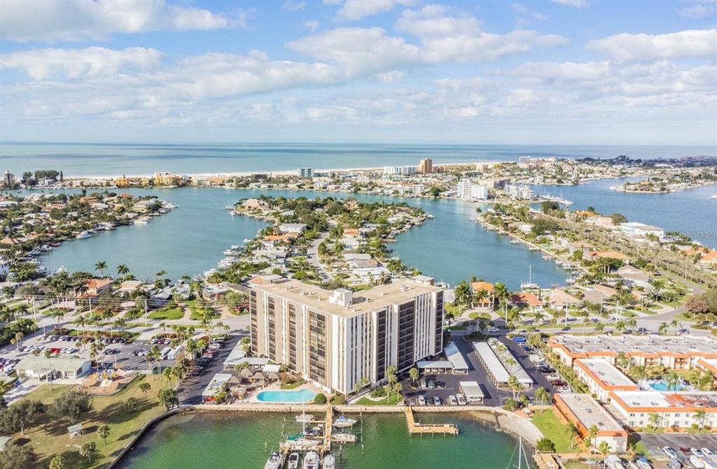 An aerial view of a waterfront condominium complex with a pool and boat docks — 10355 PARADISE BOULEVARD UNIT 702, TREASURE ISLAND, FL