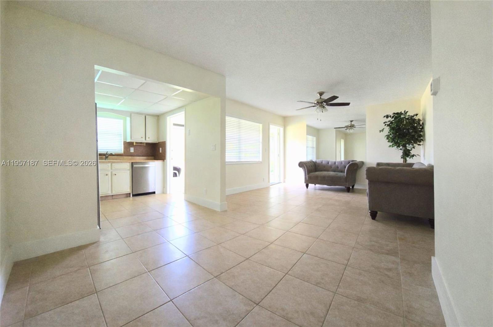An open-concept living area features light tile flooring, white walls, and an adjacent kitchen — 5300 Washington St # I205, Hollywood FL 33021, HOLLYWOOD, FL