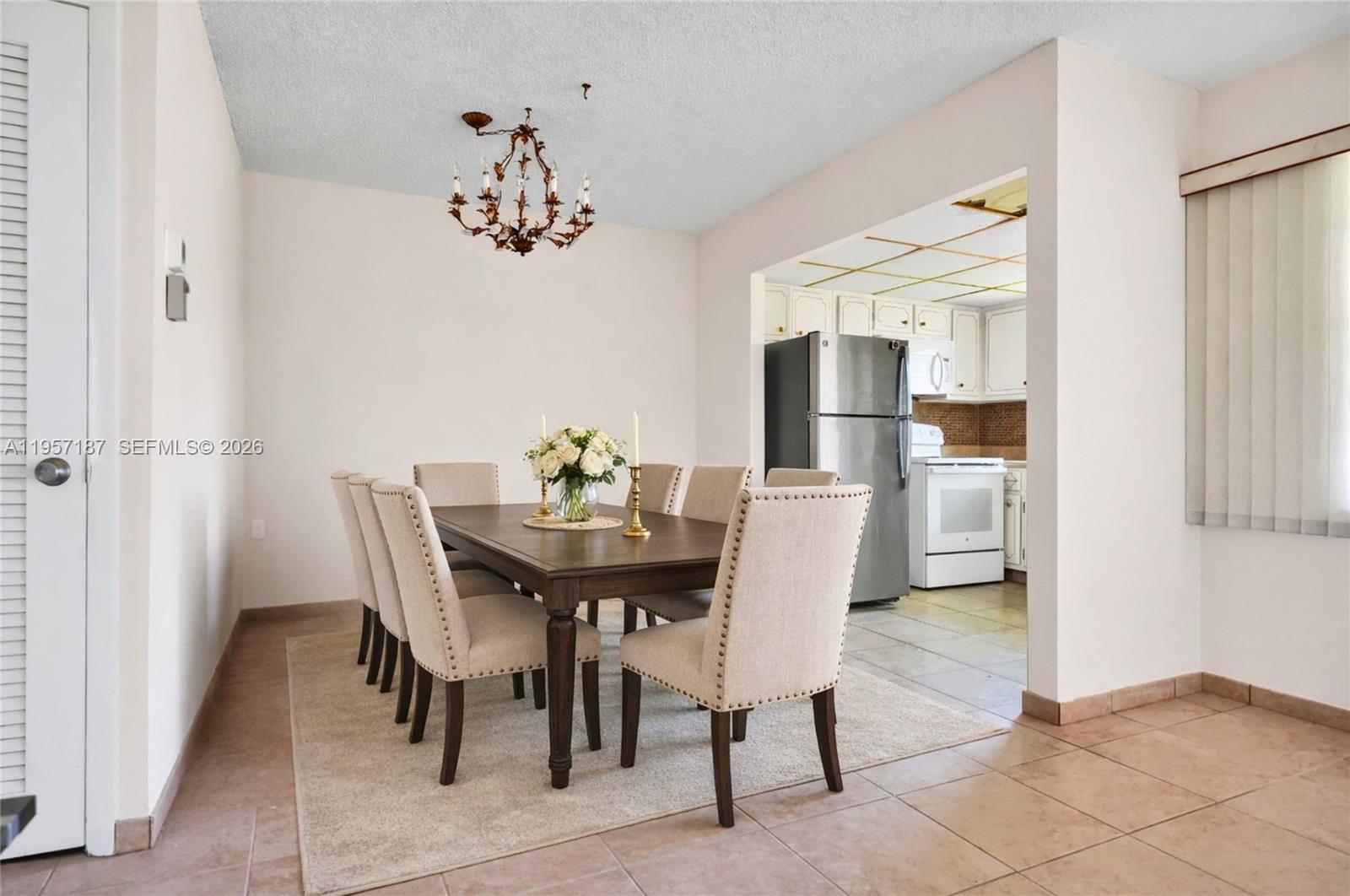 A dining room with a wooden table, upholstered chairs, and an adjacent kitchen — 5300 Washington St # I205, Hollywood FL 33021, HOLLYWOOD, FL