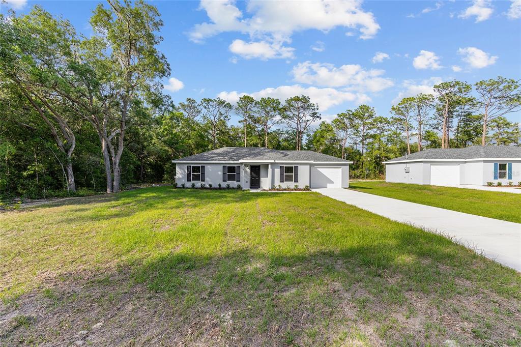 A single-story house with a gray exterior, dark shutters, and a concrete driveway — 358 LOCUST ROAD, OCALA, FL