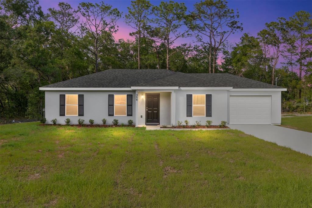 A single-story house with a white exterior, dark shutters, and a one-car garage at dusk — 358 LOCUST ROAD, OCALA, FL