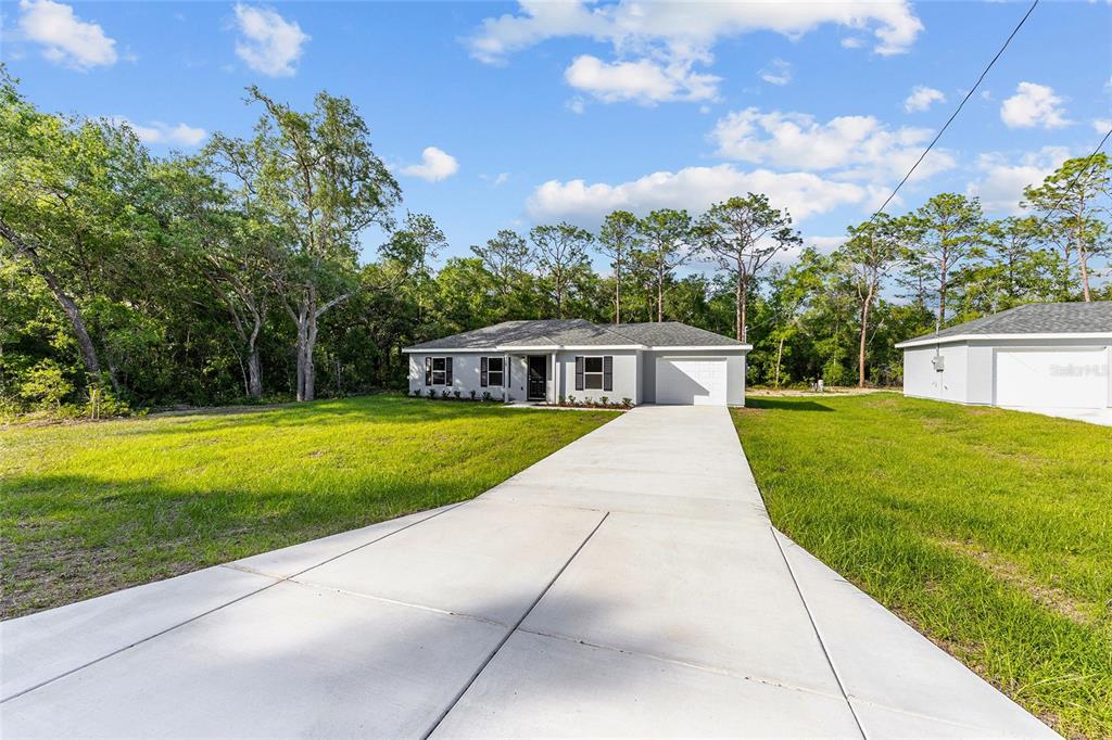 A single-story house with a concrete driveway and a garage sits on a grassy lot — 358 LOCUST ROAD, OCALA, FL