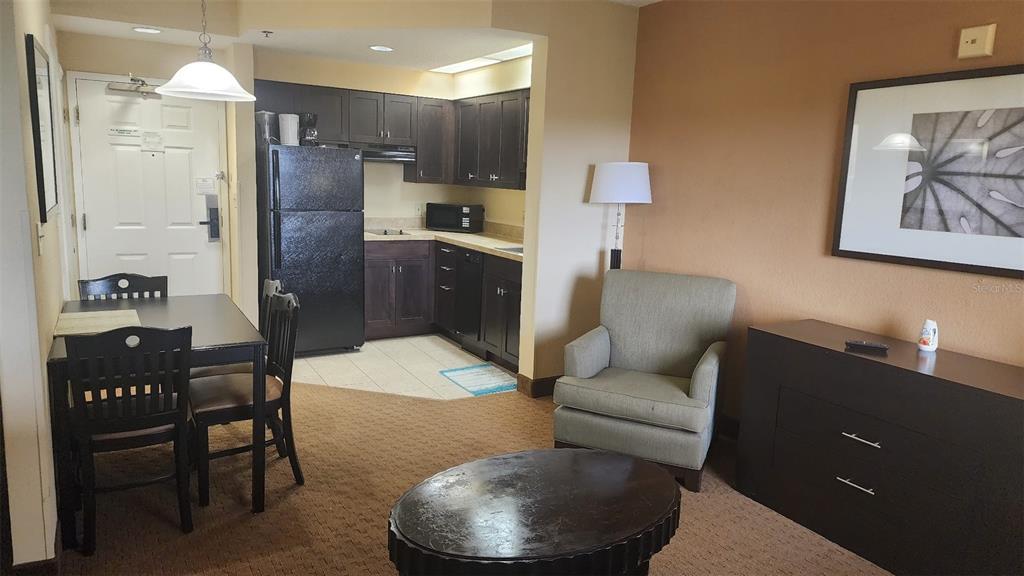 A hotel suite features a small kitchen, dining area, and a seating space with an armchair — 7601 CANADA AVENUE UNIT 618, ORLANDO, FL