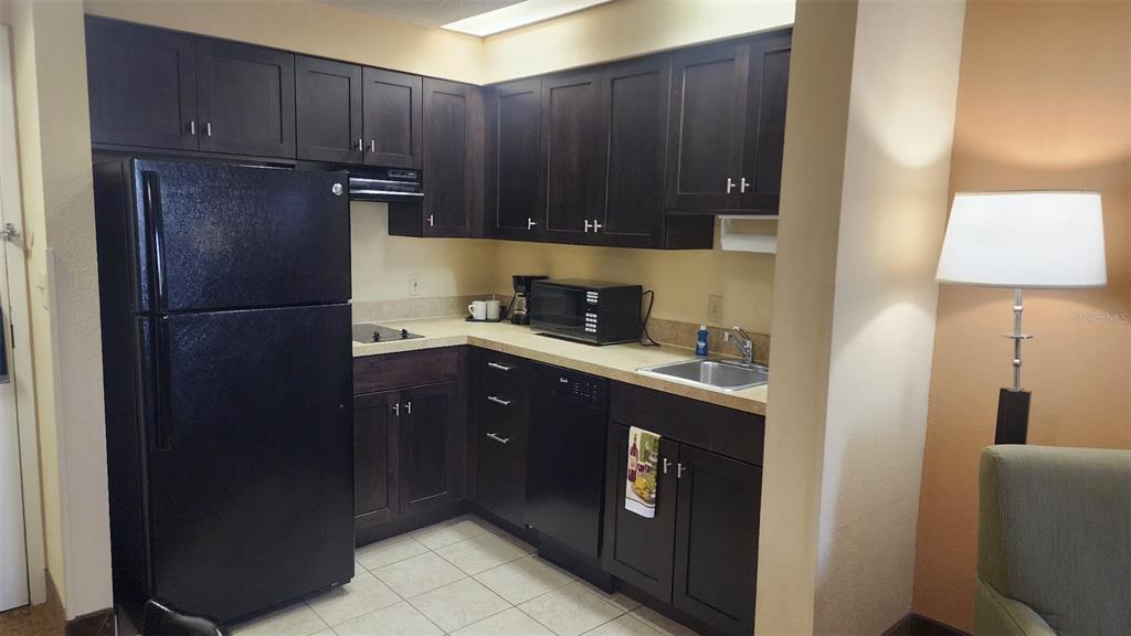 A kitchen features dark wood cabinets, black appliances, and light countertops — 7601 CANADA AVENUE UNIT 618, ORLANDO, FL