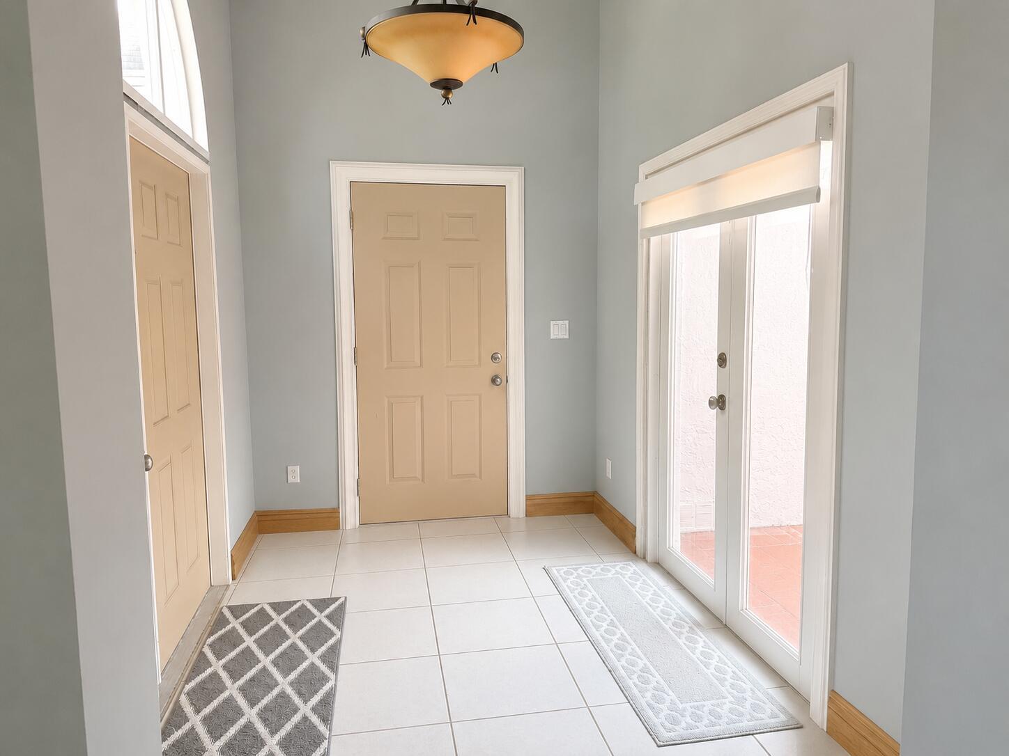 An entryway with light blue walls, tile flooring, tan doors, and a glass-paned double door — 17202 SW 149th Place, Miami FL 33187, MIAMI, FL