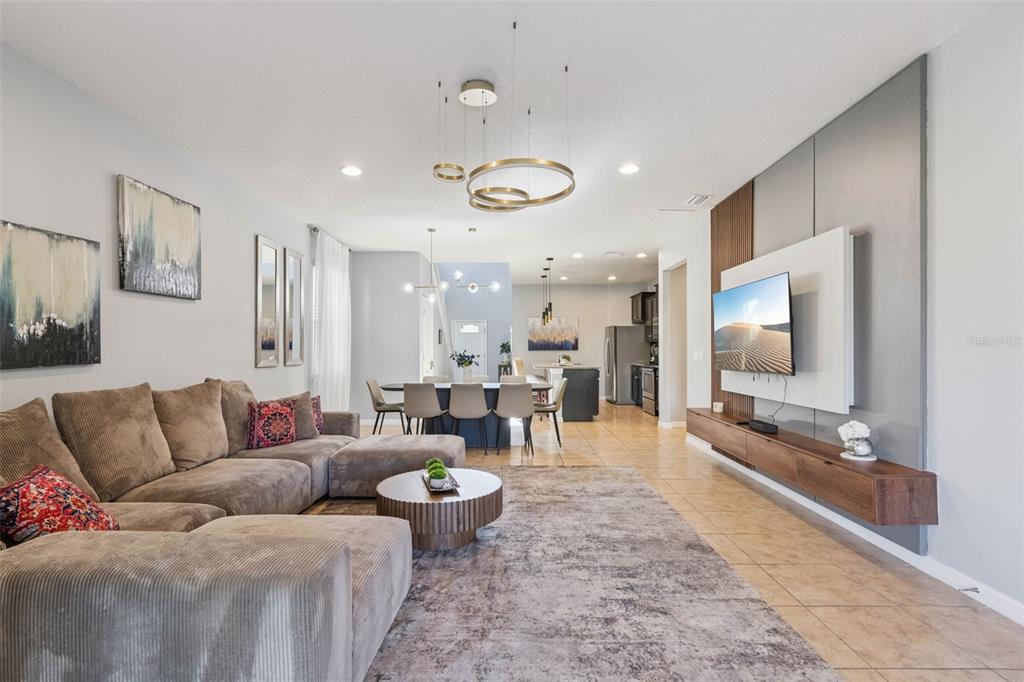 A living room with a sectional sofa, dining area, and a wall-mounted television — 1844 GOBI DRIVE, KISSIMMEE, FL