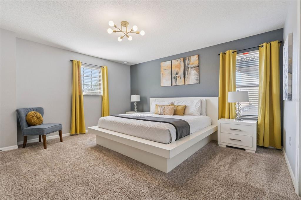 A bedroom features a platform bed, gray accent wall, yellow curtains, and a modern light fixture — 1844 GOBI DRIVE, KISSIMMEE, FL