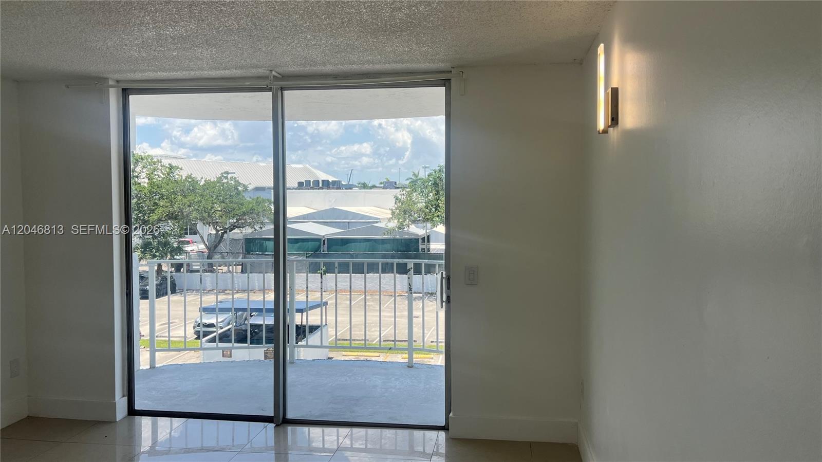 A room with tile floors, a sliding glass door to a balcony, and wall lighting — 488 NW 165th St Rd # 309, Miami FL 33169, MIAMI, FL