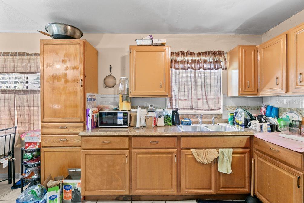 A kitchen features light wood cabinets, a double sink, and a microwave on the counter — 1211 POPPY AVENUE, ORLANDO, FL