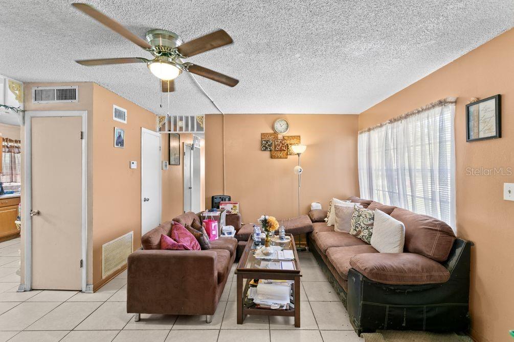 A living room features tan walls, tile flooring, two brown sofas, and a ceiling fan — 1211 POPPY AVENUE, ORLANDO, FL