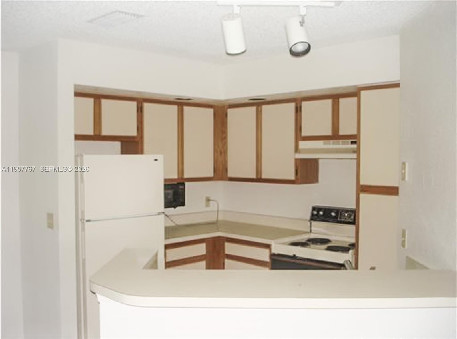 A kitchen features white appliances, light-colored countertops, and cabinets with wood trim — 3300 N Pinewalk Dr N # 1915, Margate FL 33063, MARGATE, FL