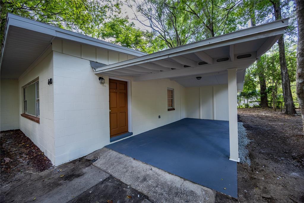 A white concrete block house with a brown front door and a covered carport area — 640 NW 36TH TERRACE, GAINESVILLE, FL