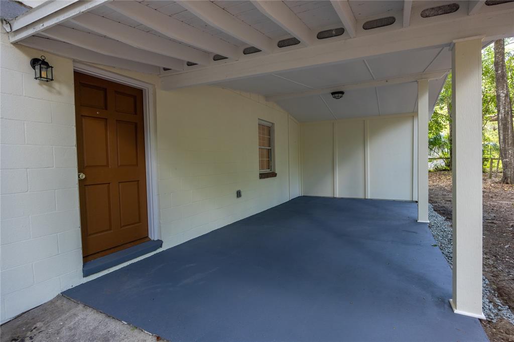 A covered concrete patio features a brown door, a window, and a white ceiling — 640 NW 36TH TERRACE, GAINESVILLE, FL