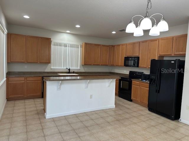 A kitchen features light wood cabinets, a central island, and black appliances — 236 BAYBERRY LAKES BOULEVARD, DAYTONA BEACH, FL