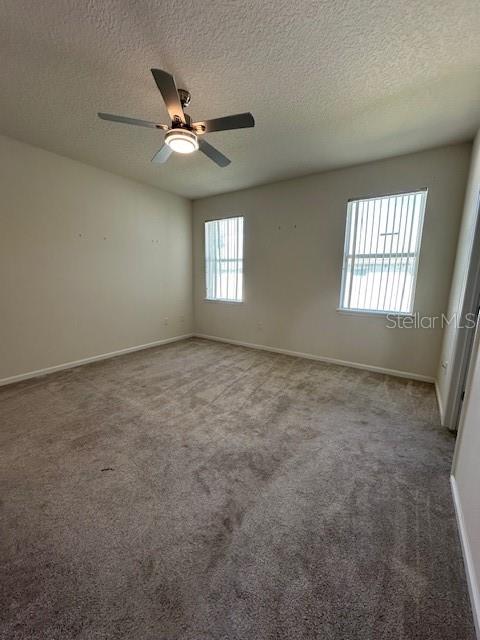 An empty bedroom features beige carpet, two windows, and a ceiling fan — 236 BAYBERRY LAKES BOULEVARD, DAYTONA BEACH, FL