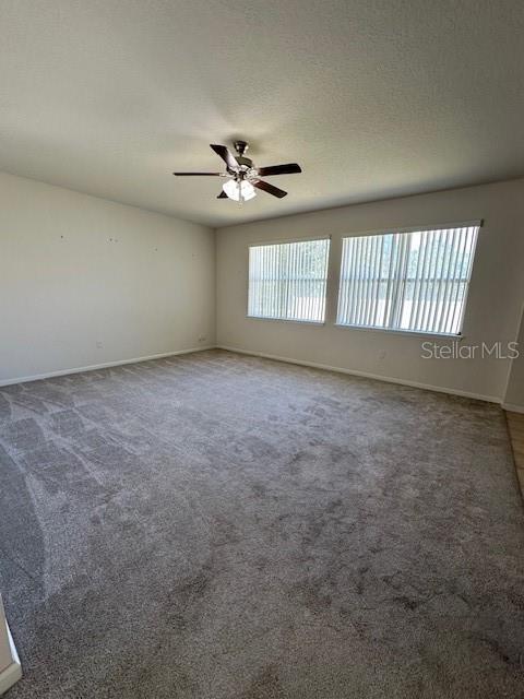 An empty room features gray carpeting, white walls, and a ceiling fan — 236 BAYBERRY LAKES BOULEVARD, DAYTONA BEACH, FL